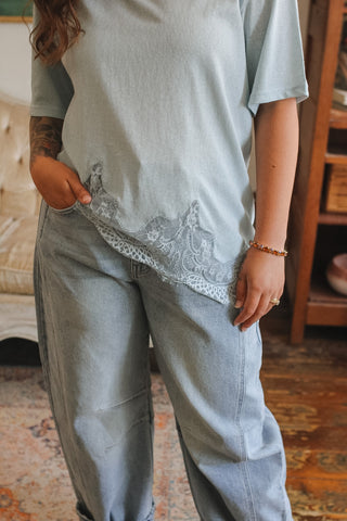 Person wearing a light blue oversized shirt with lace trim and matching pants indoors.