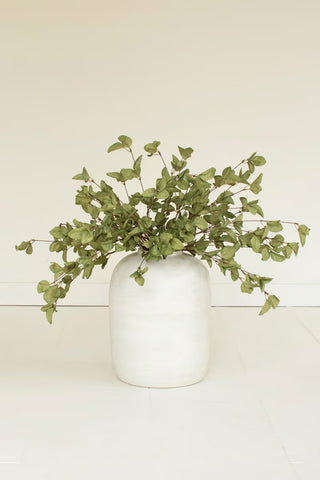A dried artificial eucalyptus branch with small light green leaves.