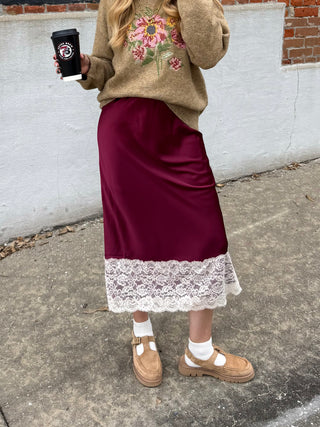 Woman wearing maroon satin lace trim midi skirt