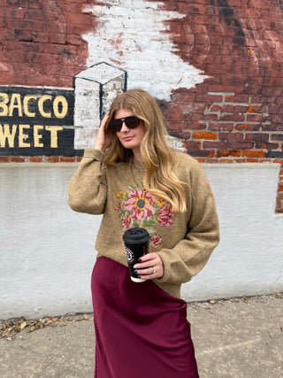 Woman wearing tan floral needlepoint knit sweater