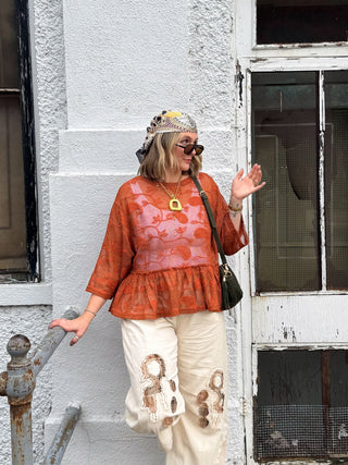 Woman wearing rust sheer paisley baby doll top