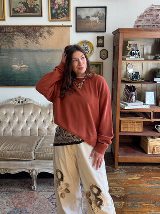 Woman wearing the Alix burnt orange layered lightweight knit sweater with a layered neckline and hem, styled with cream denim