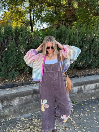 Woman wearing the Penny rainbow ribbed knit cardigan with balloon sleeves and pink trim, styled with a white tank and brown corduroy overalls