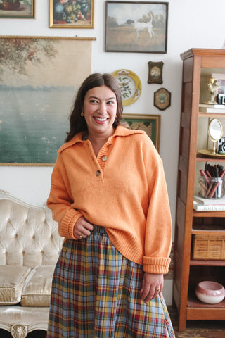 Woman wearing apricot collared knit sweater with button placket
