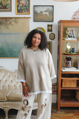Woman wearing gray oversized sweater with lace trim
