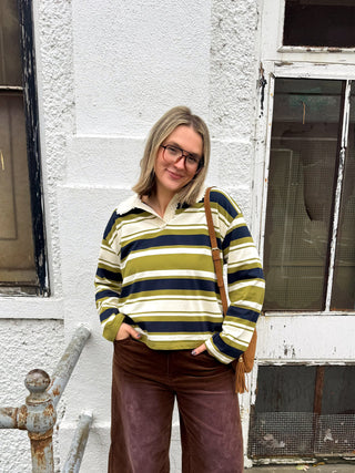 Woman wearing the Andie olive, navy and cream striped collared long sleeve top with a lace trim collar and brown corduroy pants
