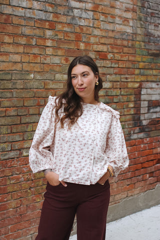 Woman wearing ivory floral blouse with ruffle collar