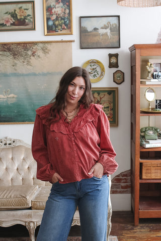 Woman wearing the Finley washed red cotton eyelet top with a ruffled collar, balloon sleeves and wide leg jeans