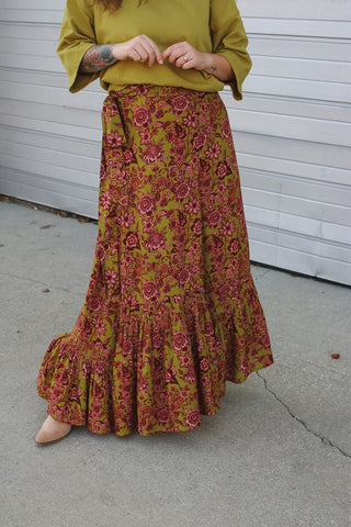 Woman wearing an olive green and burgundy floral wrap maxi skirt with a ruffle hem and an olive green tee