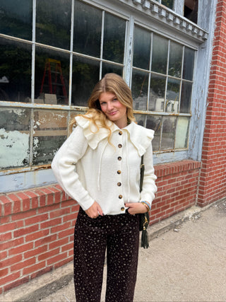 Woman wearing white knit cardigan with ruffle collar