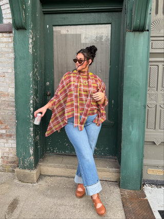 Woman wearing sheer berry plaid poncho top with tie scarf