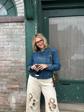 Woman wearing denim military jacket with gold buttons