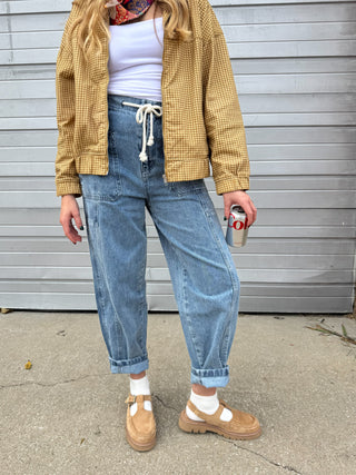 Woman wearing medium wash high rise drawstring barrel jeans