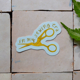 Sticker of a pair of scissors with in my sewing era text on it.