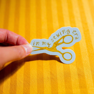 Sticker of a pair of scissors with in my sewing era text on it.