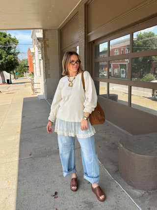 Woman wearing ivory crewneck sweatshirt with layered lace hem