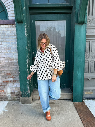 Woman wearing cream and black polka dot blouse with ruffle sleeves