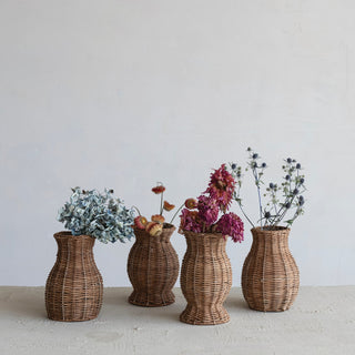 Four wicker vases with flowers on a light surface and white background